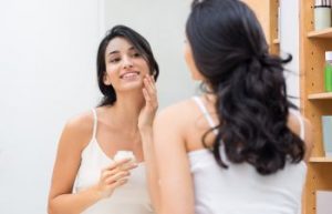woman taking care of her skin in front of the mirror
