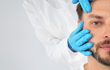 A surgeon examining man's face.