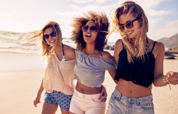 Three joyful beautiful women having fun on a beach.