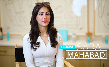 Woman seated wearing white top and sunglasses on head, with text overlay: "Kalos Client Sara Mahabadi." Blurred background with abstract art and products.