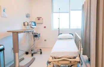 A hospital room with a bed, medical equipment, and a window with blinds.