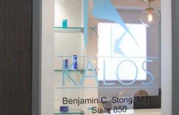 Frosted glass door with a logo and contact information for surgery, hair, and spa services, titled Kalos. A "No Soliciting" sign is also visible.