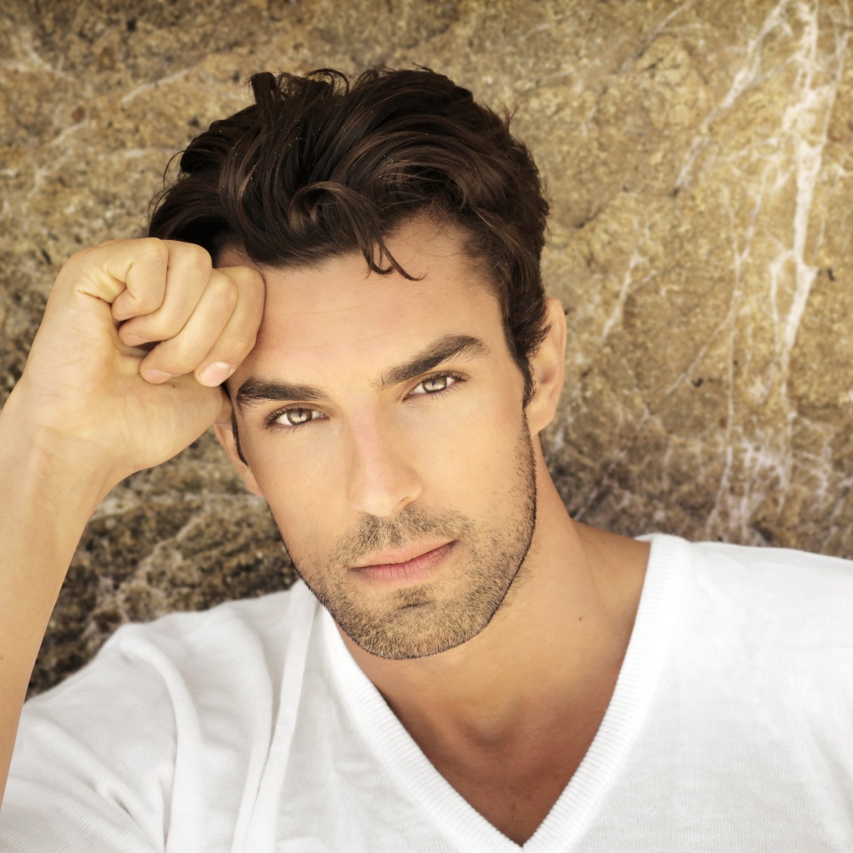 Portrait of young man outdoors with very handsome face in white casual shirt against natural background