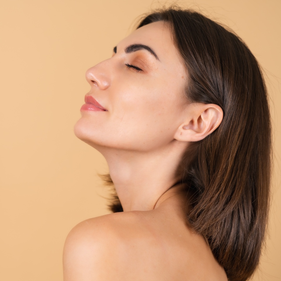 Portrait of a young girl on a beige background with natural makeup, with a light sensual smile, bare shoulders, beauty face, advertising of cosmetics and care