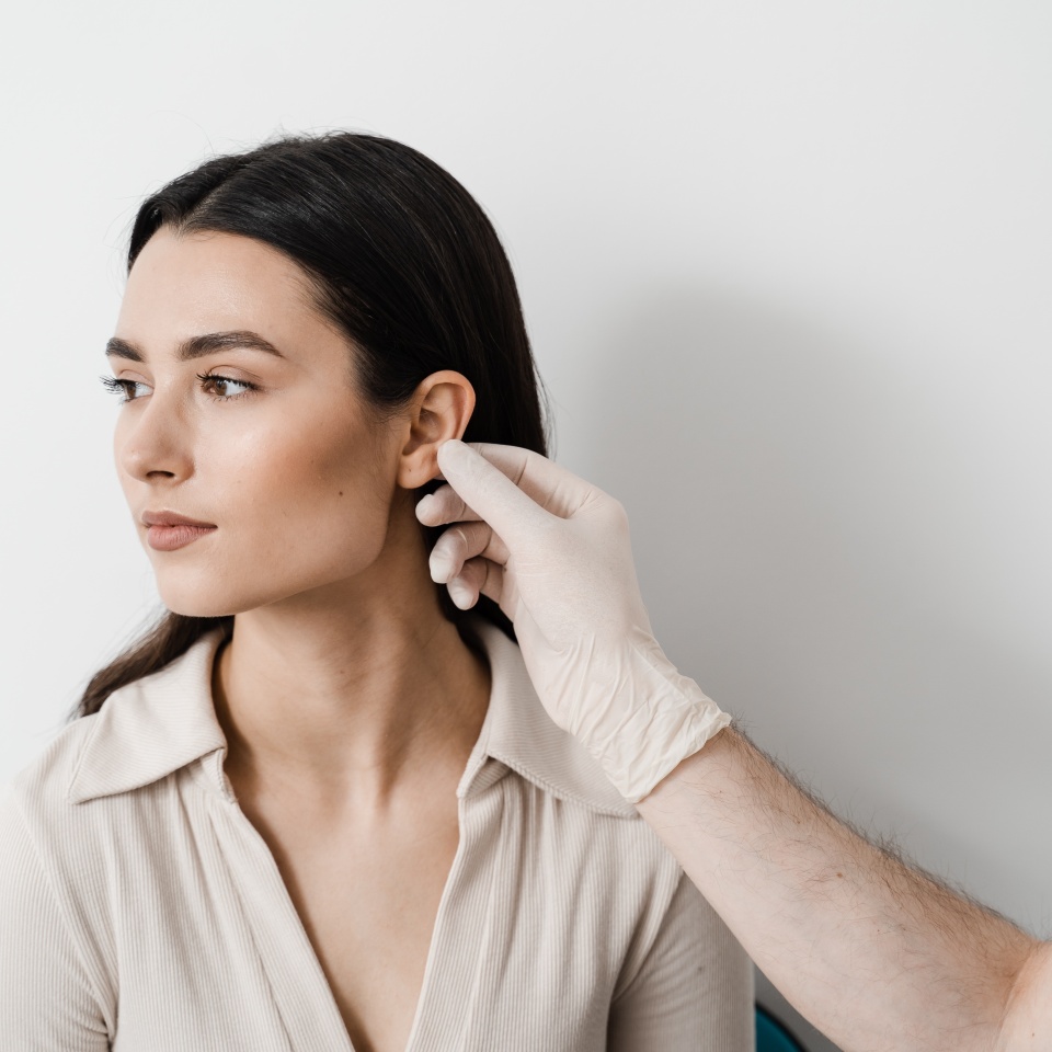 Otoplasty is surgical reshaping of the pinna, or outer ear for correcting an irregularity and improving appearance. Surgeon doctor examines girl ear before otoplasty cosmetic surgery