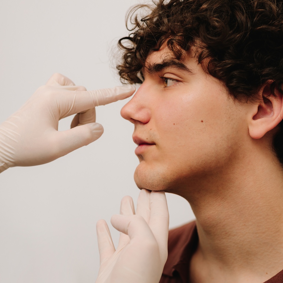 Rhinoplasty consultation for man before plastic surgery to correct the nose size and shape. Rhinoplasty reshaping nose and septoplasty. ENT doctor touching nose of male patient before rhinoplasty