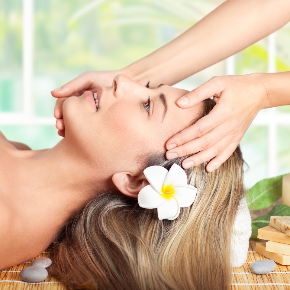 Beautiful blond woman lying down on massage table in spa salon, enjoying facial massage, doing facial mask, healthy lifestyle and beauty treatment concept