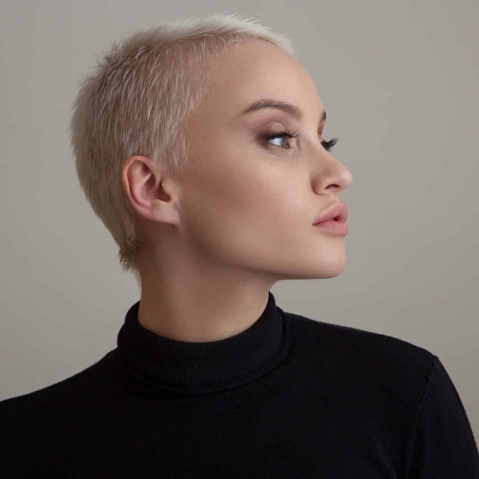 Portrait of a beautiful blonde woman with a short hair on a gray background.