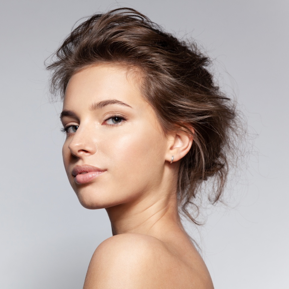 Portrait of beautiful young caucasian female with bare shoulder on gray background with copyspace for ad. Pretty millennial girl model with clean healthy moisturized skin. Natural beauty concept
