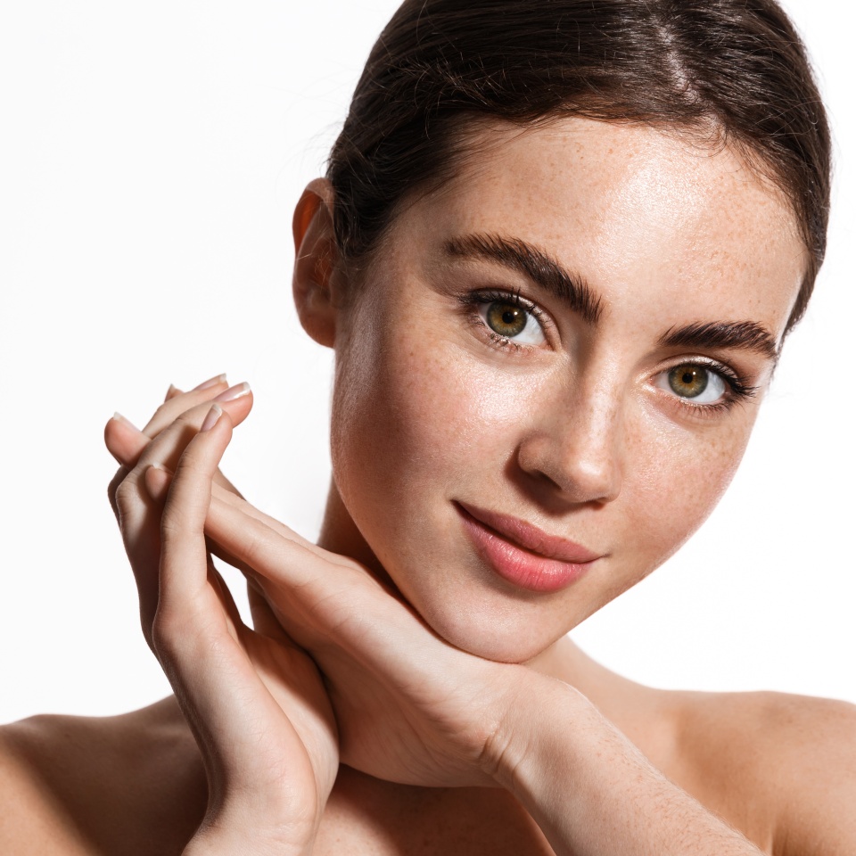 Beauty face and spa. Woman with freckles, clean nourished skin, biting lip and look aside. Girl model using antiaging cosmetics and vitamin c serum for bettet smoother skin tone, white background