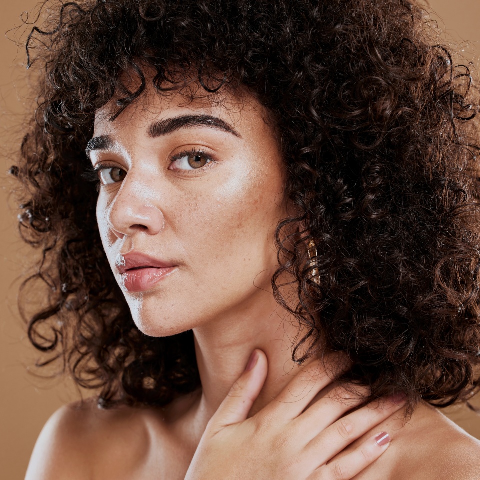 Face, beauty and skincare with a model black woman in studio on a brown background for natural hair care. Eyes, portrait and makeup with an attractive young female posing to promote cosmetics