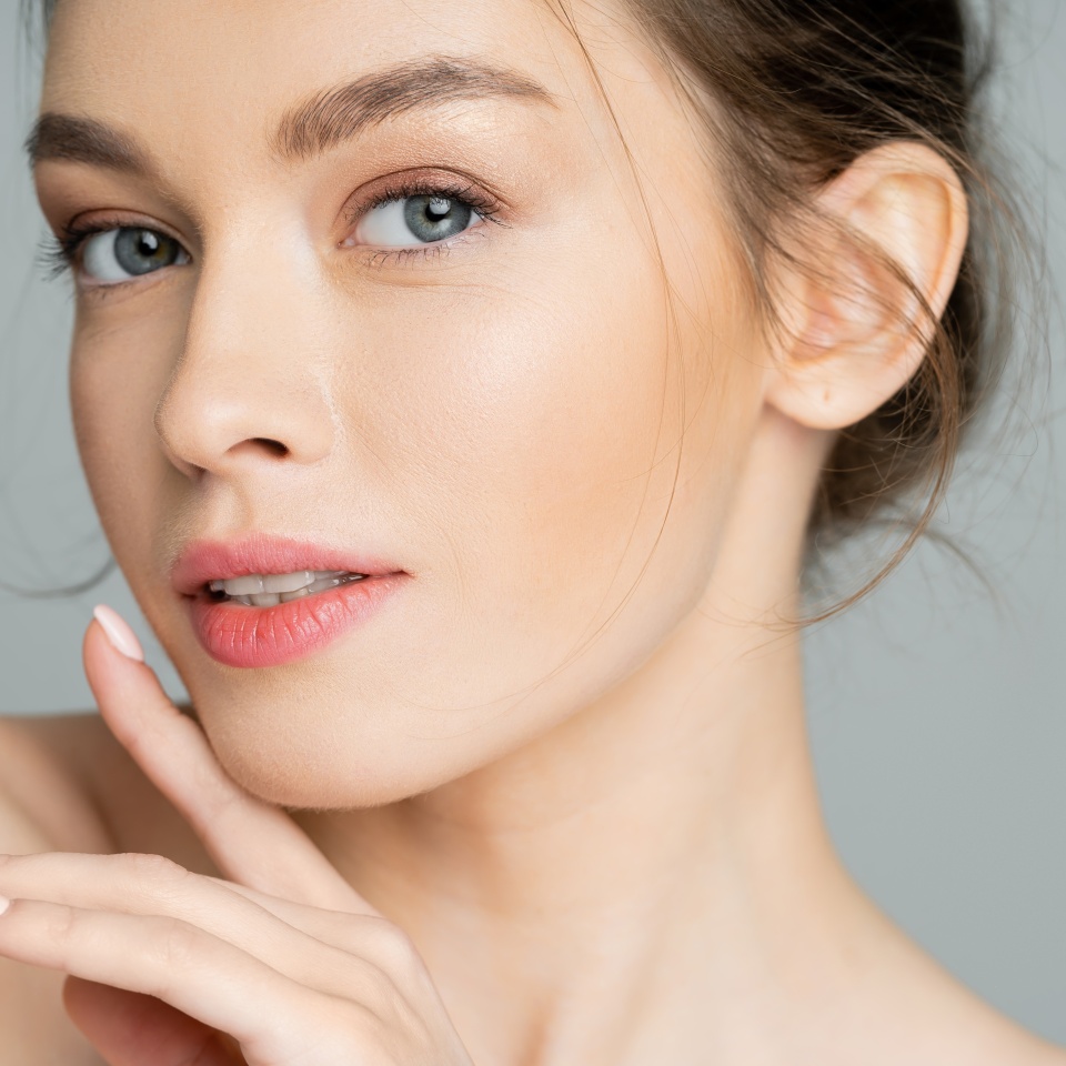 Portrait of young woman with natural visage posing isolated on grey