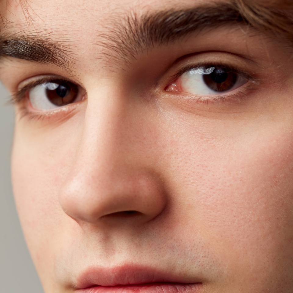 Looking in camera. Close-up portrait of young man with brown eyes. Eyes, nose. Vision care. Concept of men's health, body and skin care, hygiene and male cosmetology