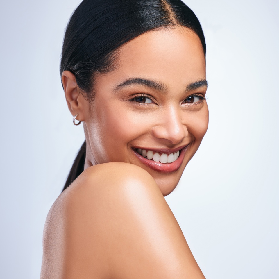 Woman, skincare and beauty in studio portrait with smile, happiness or natural glow on skin by white background. Girl, model and happy for makeup, cosmetics or youth with wellness, aesthetic or shine