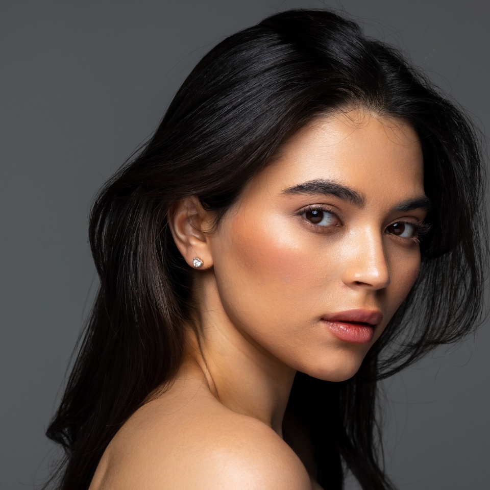 Close up beauty portrait of a laughing beautiful half naked woman applying face cream and looking away isolated over white background