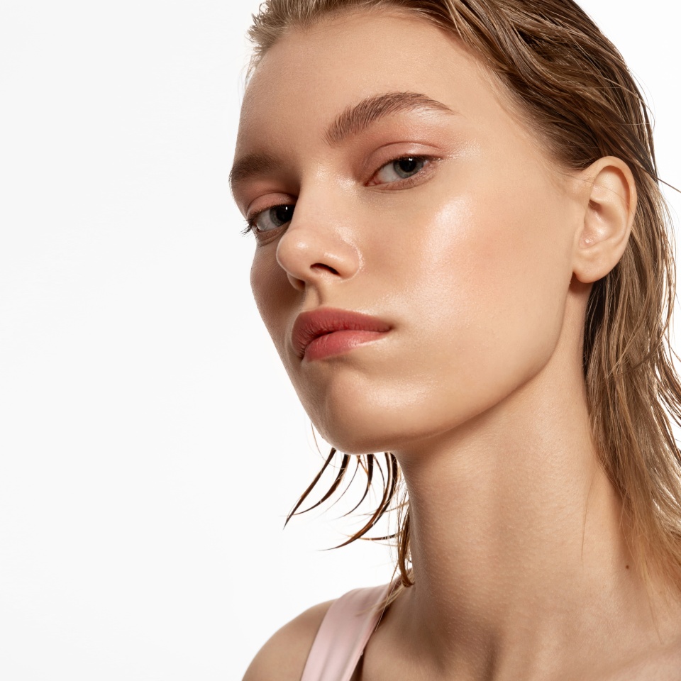 Blonde girl with glowing skin and natural beauty looks at the camera