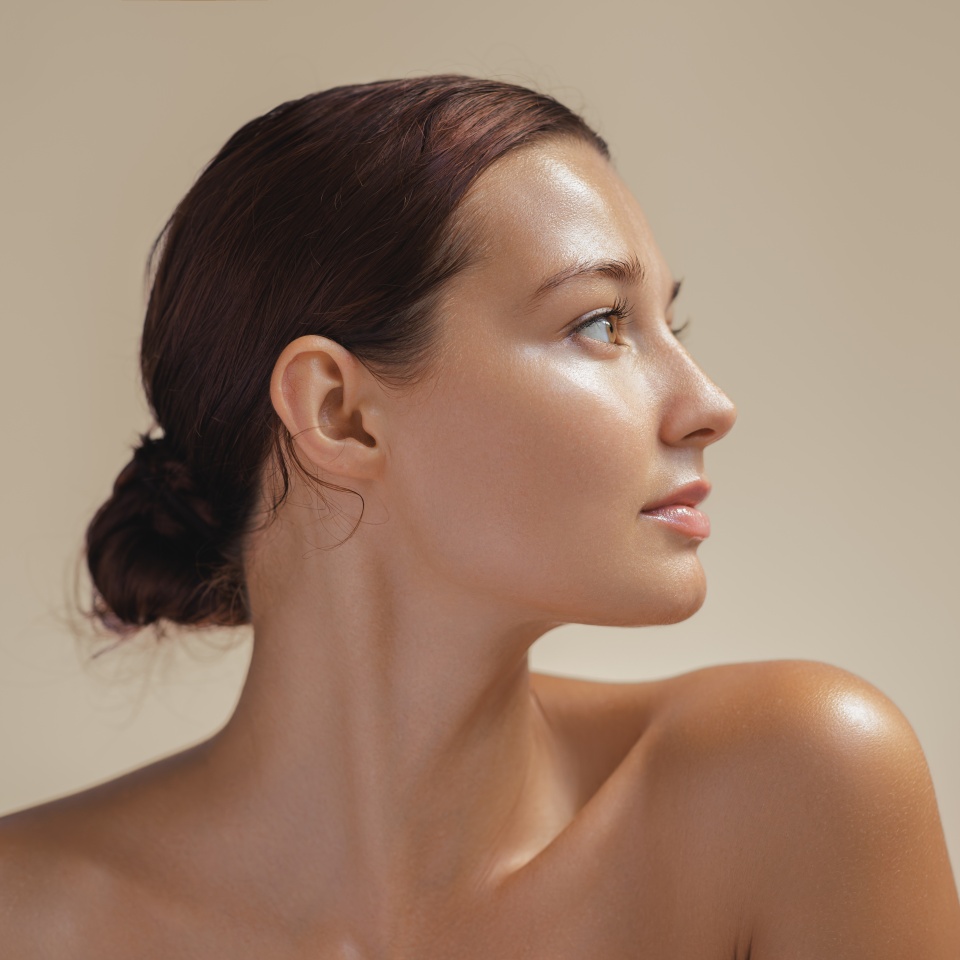 Side view portrait of a young woman with glowing, healthy skin in soft light. Ideal for beauty, skincare, and wellness campaigns. High-quality image for cosmetics or natural beauty promotions.