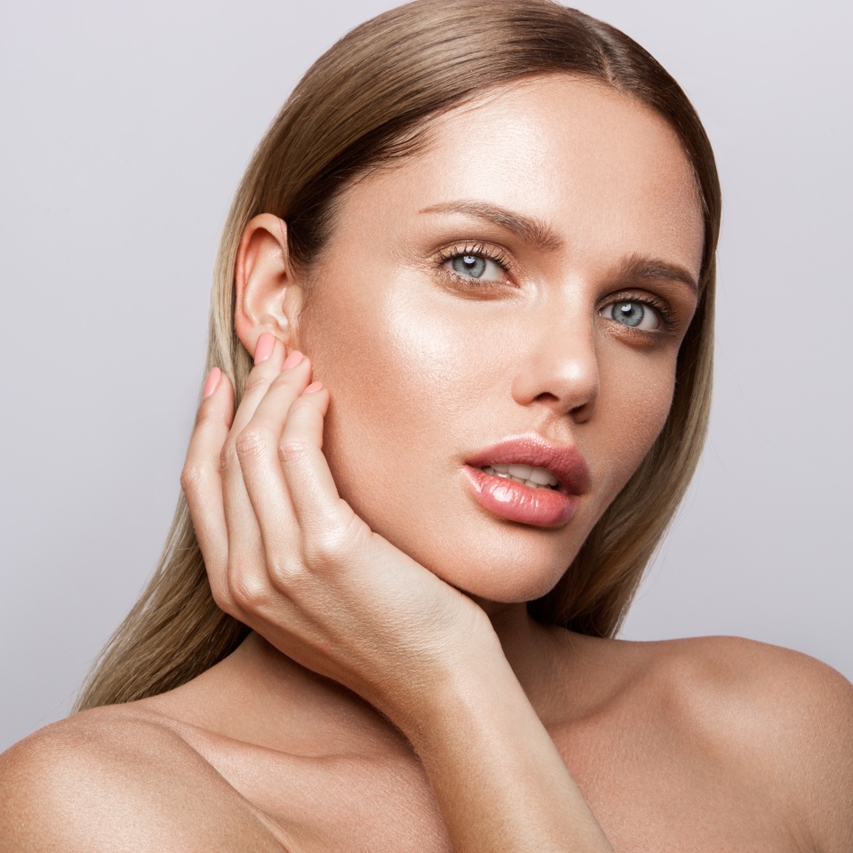 Beauty portrait of model with natural make-up. Fashion shiny highlighter on skin, sexy gloss lips make-up