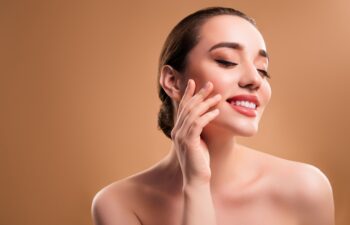 Lovely pretty girl enjoy touch her flawless face skin after moisturizing mask isolated on beige color background