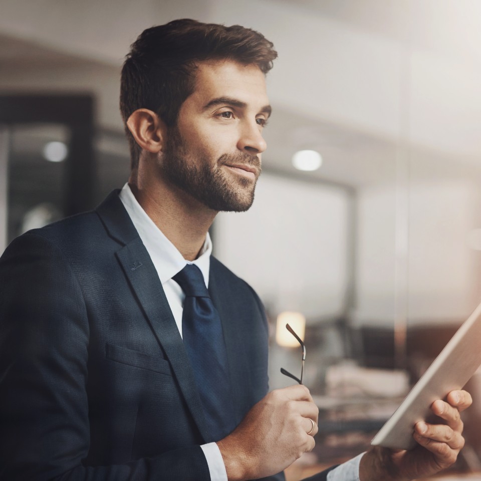 Businessman working on tablet in office, thinking and brainstorming, professional employee with digital project ideas, blurred background