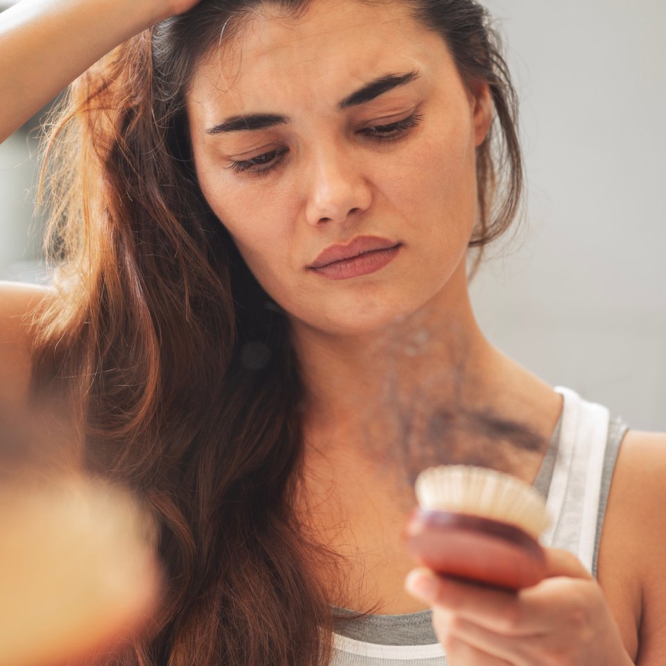 Woman losing hair with hairbrush in hand