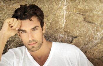 Portrait of young man outdoors with very handsome face in white casual shirt against natural background