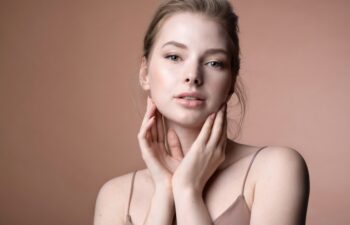 Pretty young caucasian female touching perfect flawless healthy skin. Girl enjoying result after beauty spa treatment, chemical peeling, cosmetics procedure. Cosmetology and dermatology advertising