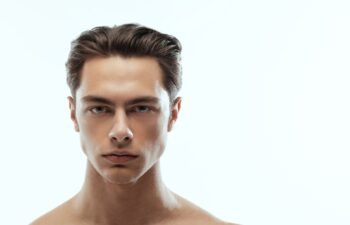 Close-up portrait of young handsome man isolated on white studio background. Concept of men's health and beauty, self-care, body and skin care. Male model looking at camera