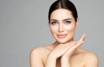 Beauty Woman Face Skin Care. Beautiful Woman Portrait with Full Lips and Long Eyelashes over Gray. Hands Manicure and Facial Treatment Cosmetics. Spa Massage and Face Lift Cosmetology