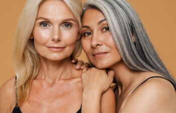 Mature multiracial beautiful women wearing bodysuits smiling and posing isolated over yellow background