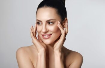 Happy Beautiful Girl Holding Her Cheeks With A Laugh Looking To The Side. Pretty Woman Clean Fresh Skin.Cosmetology, Beauty And Spa.