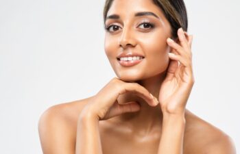 Woman Face Skin Care Cosmetic. Indian Beauty Model showing Perfect Chin and Cheekbones. Women Facial Treatment and Health. Beautiful Girl doing Anti Aging Face Lift Massage over White