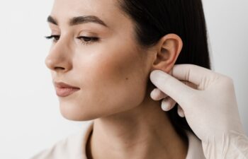 Otoplasty ear surgery. Otoplasty surgical reshaping of pinna and ear. Surgeon doctor examines girl ears before otoplasty cosmetic surgery