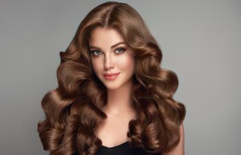 Beautiful brunette model girl with long curly hair . Smiling woman hairstyle wavy curls . Fashion , beauty and makeup portrait. Treatment, care and spa procedures.