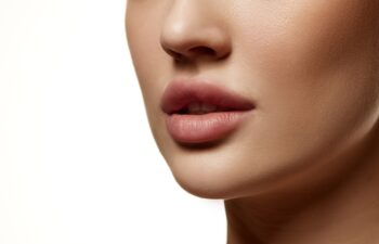 Cropped close-up image of beautiful female face, plump lips with nude lipsticks makeup isolated against white studio background. Lip augmentation. Concept of beauty, cosmetology, cosmetics, skin care
