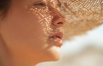 Beach sun hat woman during vacation. Close-up of a girl's face in straw sunhat enjoying the sun looking away.