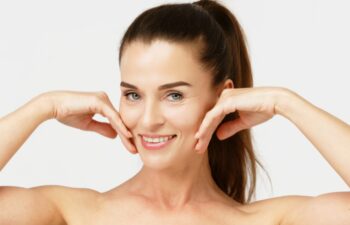 Gorgeous middle aged woman touching her perfect skin. Beautiful portrait of a 40-50 year old woman advertising anti-aging facial products, salon care, skin tightening, isolated on white background.