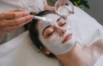 Woman getting facial care by beautician at spa salon. Face peeling mask, spa beauty treatment, skincare.