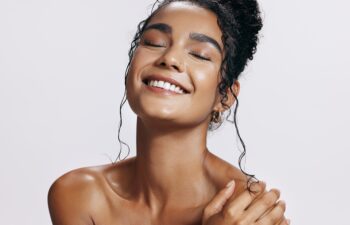 Studio, shine and joy of woman, beauty and treatment of skincare, soft and glow of body in results. Pink background, aesthetic and proud for skin, dermatology and cosmetics for person and hand