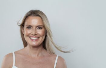 Nice cheerful healthy blonde mid adult mature woman looking at camera on white background. Mature lady portrait. Healthy face, skin care beauty, middle age skincare cosmetic and cosmetology concept