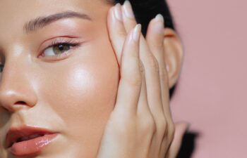 Close-up portrait of a woman with radiant skin and hands on her face, emphasizing her glowing complexion and natural beauty. Perfect for skincare, cosmetics, and beauty concept advertisements and high