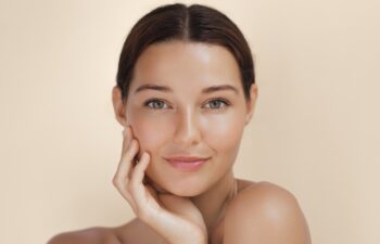 Close-up portrait of a woman with radiant, glowing skin gently touching her face. Her flawless complexion and smooth skin make this image perfect for beauty, makeup, and skincare promotions