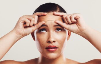 Wrinkles, forehead and woman with skincare, beauty and plastic surgery on white studio background. Person, worry and model with cosmetic facial filler, wellness and health with dermatology and stress