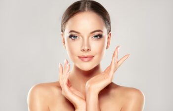 Beautiful Young Woman with Clean Fresh Skin touch own face . Facial treatment . Cosmetology , beauty and spa .