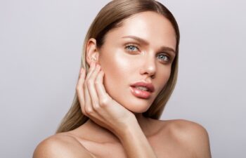 Beauty portrait of model with natural make-up. Fashion shiny highlighter on skin, sexy gloss lips make-up