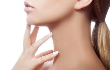 Beautiful young teen woman face with healthy clean skin, natural make up and green eyes touching her neck isolated on white. Studio health and care portrait