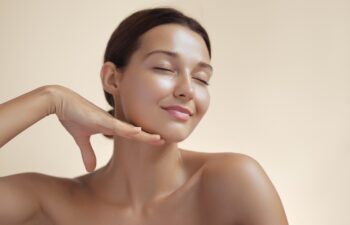 High-quality photo of skincare and cosmetics concept with copy space for text. Natural beauty woman woman with radiant, glowing skin closes her eyes and gently touches her face with her hand, creating