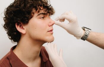 Rhinoplasty surgery preparation for man. ENT is touching nose and consulting man. Final examination before septoplasty surgery